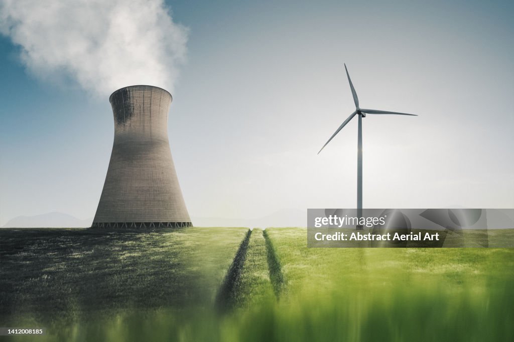 Low angle shot showing a power station and a wind turbine side by side in an agricultural field, United Kingdom