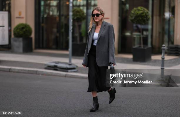 Sophie Pirrung is seen wearing a grey oversized toteme blazer, a white shirt, Anine Bing skirt, black acne boots, black Anine Bing handbag on July...