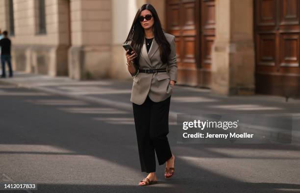 Leo Eberlin is seen wearing Hermes brown leather Oran sandals, a Chanel vintage black zipped belt, Bottega Veneta brown shades, Sandro olive blazer...