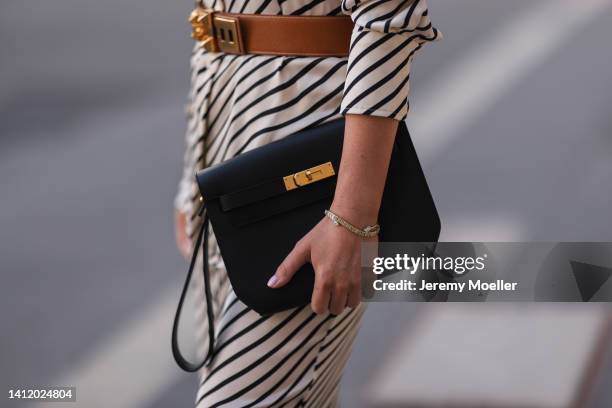 Leo Eberlin is seen wearing H&M striped matching two piece, Hermes vintage beige leather gold belt, Hermes black leather clutch on July 28, 2022 in...