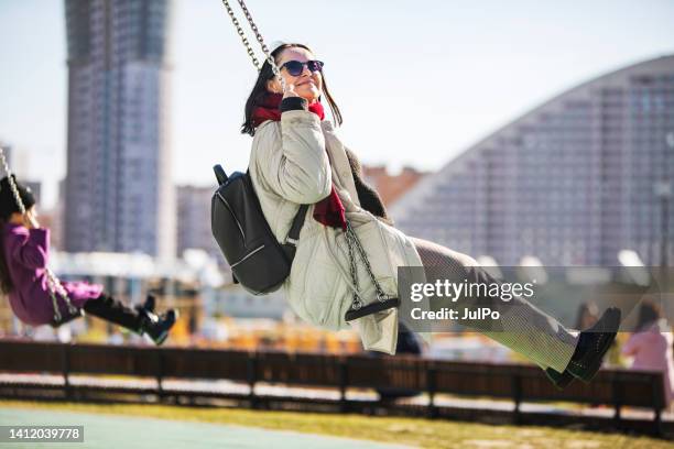 young adult woman swinging in autumn public park - woman on swing stock pictures, royalty-free photos & images