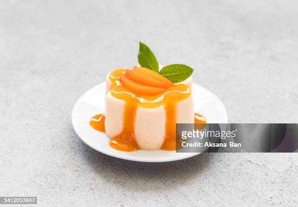 vegan dessert. apricot pudding, panna cotta with topping, decorated with slices of fruit and apricot jelly in the shape of pearls, on a plate. light grey background. top view - panna cotta stock pictures, royalty-free photos & images