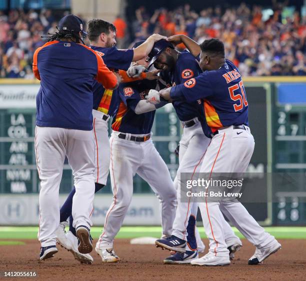 Yordan Alvarez of the Houston Astros, center, is congratulated by his teammates after a walk-off single in the tenth inning against the Seattle...