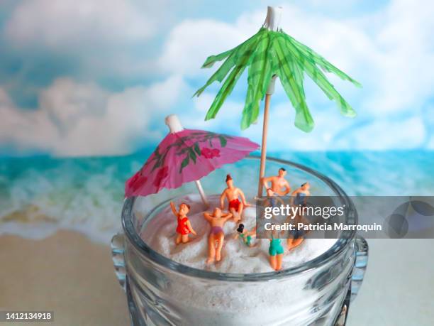 miniature people on the beach - tiki umbrella stock pictures, royalty-free photos & images