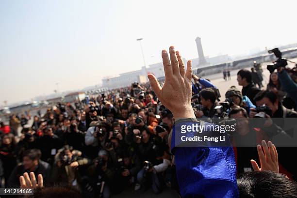 The ethnic minority delegates wave to photographers as they leave the closing ceremony of the Chinese People's Political Consultative Conference at...