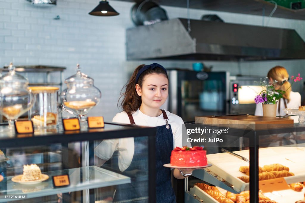 Panadero tomando pastel de fresa del mostrador de la tienda
