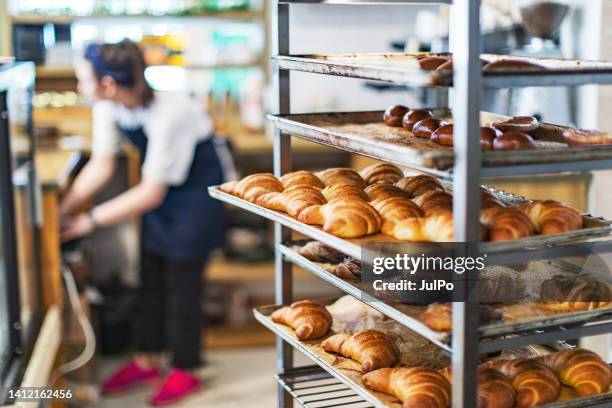 fresh french bread and croissants in a bakery in cooling rack - sweet bun stockfoto's en -beelden