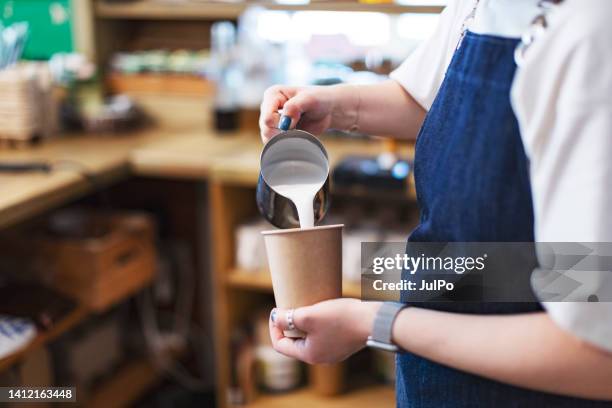 close-up of barista gently drawing pattern pouring milk into glass with latte - barista coffee milk stock pictures, royalty-free photos & images