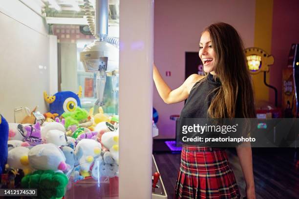 portrait of young woman playing with toy claw machine - claw machine stock pictures, royalty-free photos & images