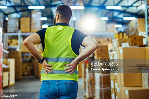 vista posteriore del magazziniere maschio che ha mal di schiena da duro lavoro - zona lombare foto e immagini stock