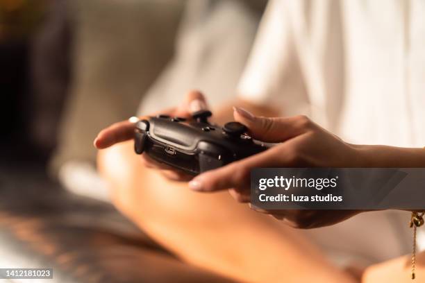 woman using a game controller to play video games - game controller stock pictures, royalty-free photos & images