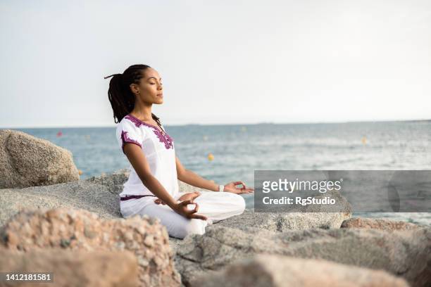 hermosa mujer meditando en el mar - women in harmony fotografías e imágenes de stock
