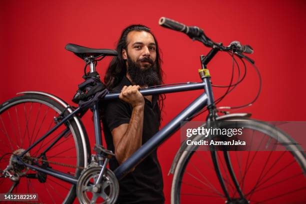 portrait of a middle eastern man carrying a bicycle - couples studio portrait stock pictures, royalty-free photos & images