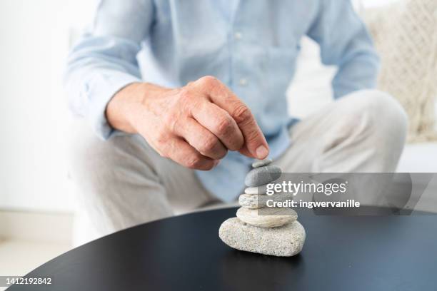 hands of unrecognizable person stacking stones on table - senior spirituality stock pictures, royalty-free photos & images