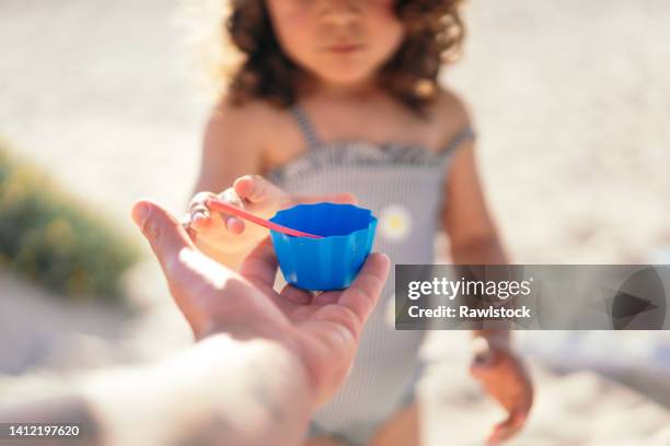 photo of a hand giving a blue toy to an unrecognizable little girl - kidnapping imagens e fotografias de stock