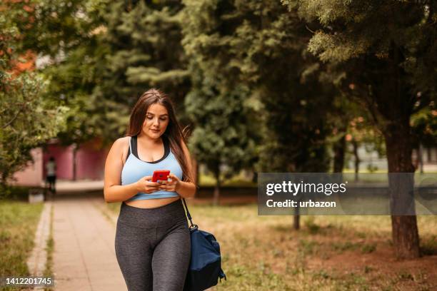 junge frau, die fitnessaktivität nach dem training in einem park überprüft - gym bag stock-fotos und bilder