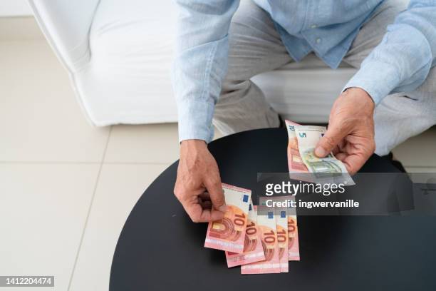 unrecognizable man counting euro banknotes on the table - counting stockfoto's en -beelden