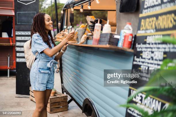 une afro-fille achète des pommes de terre au fast-food truck - cuisine de rue photos et images de collection