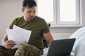 Army combatant holding documentation while starting at laptop screen