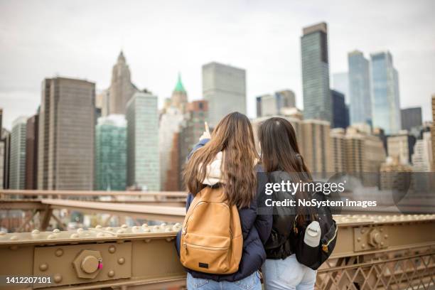 tourist, der lower manhattan von der brooklyn bridge aus beobachtet - touristen brooklyn bridge stock-fotos und bilder