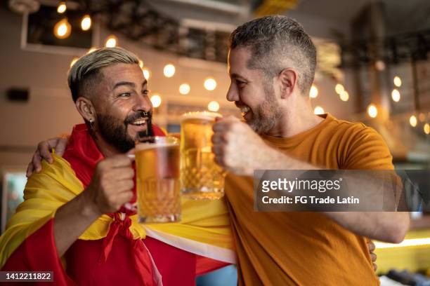 hispanic friends watching sports game and doing a celebratory toast at a bar - hispanic day stock pictures, royalty-free photos & images