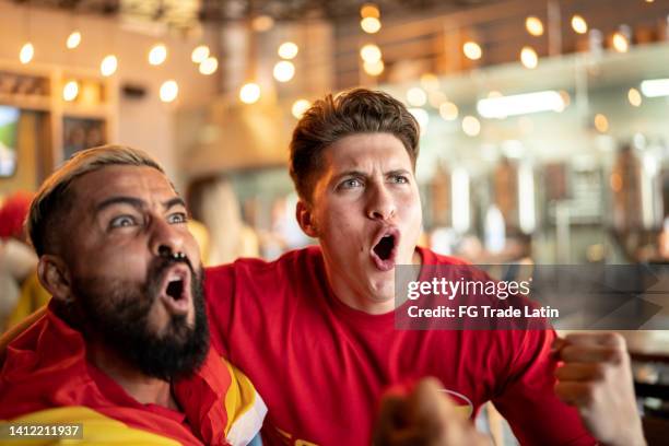hispanic friends watching sports game and celebrating at a bar - spanish culture stock pictures, royalty-free photos & images