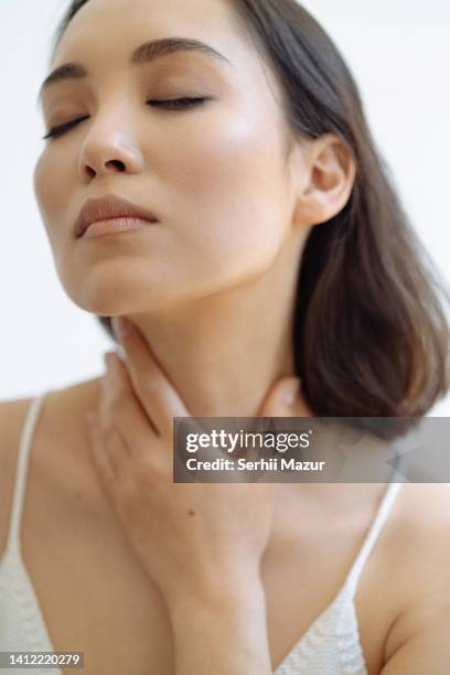 close up of woman touch her neck - stock photo - schilddrüsenüberfunktion stock-fotos und bilder