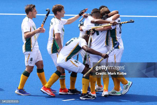 Nicholas Spooner of Team South Africa celebrates with team mates after scoring their sides second goal during the Men's Hockey - Pool A match between...