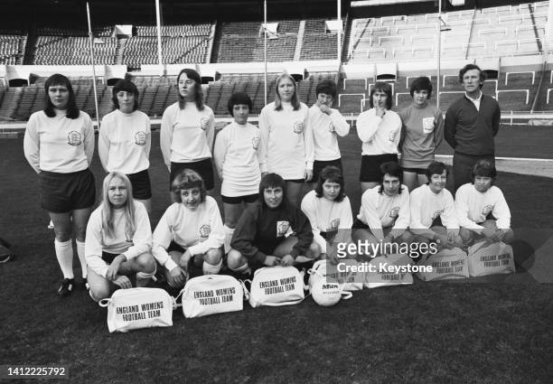 The England women's national football team pose before England Women's Football Team sports bags and a Mitre Multiplex football, alongside their...