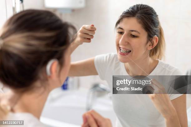 young woman is brushing her teeth in a bathroom - dental floss stock pictures, royalty-free photos & images