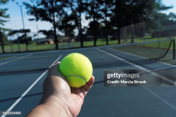 hand holding tennis ball on tennis court - balle de tennis photos et images de collection