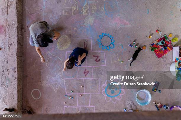 madre e hija haciendo arte de tiza en el suelo - chalk art equipment fotografías e imágenes de stock