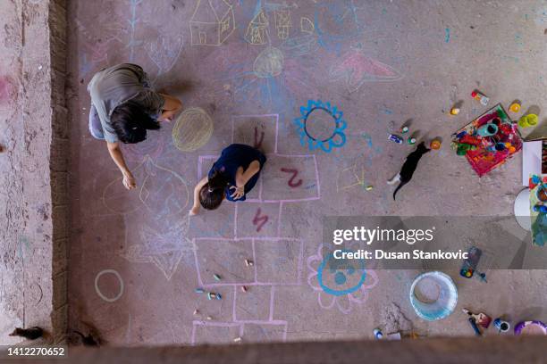 mother and daughter doing chalk art on floor - chalk art equipment stock pictures, royalty-free photos & images