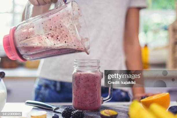 teenage girl making fresh organic smoothie using blender in the kitchen - milkshake stock pictures, royalty-free photos & images