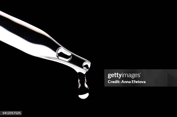drop of serum falls from glass pipette on black background. cosmetic liquid based on polyglutamic acid, ceramides and essential oils. macro photography - oil macro stock pictures, royalty-free photos & images