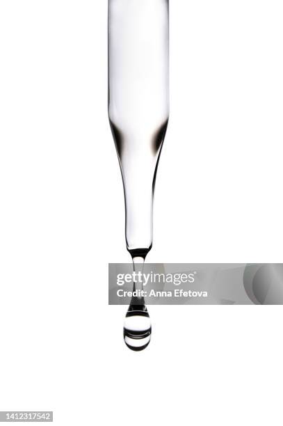 drop of serum falls from glass pipette on white background. cosmetic liquid based on polyglutamic acid, ceramides and essential oils. macro photography - ピペット ストックフォトと画像