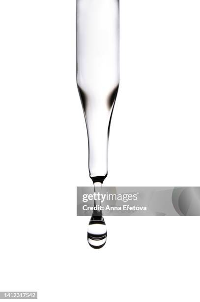 drop of serum falls from glass pipette on white background. cosmetic liquid based on polyglutamic acid, ceramides and essential oils. macro photography - science white background stockfoto's en -beelden
