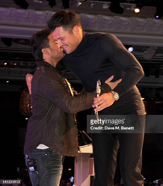 Satellite/Digital TV Personality award winner Peter Andre accepts his award from presenter Mark Wright at the TRIC Television and Radio Industries...