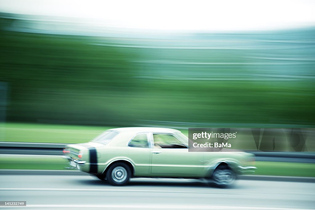 Classic car speeding down road,