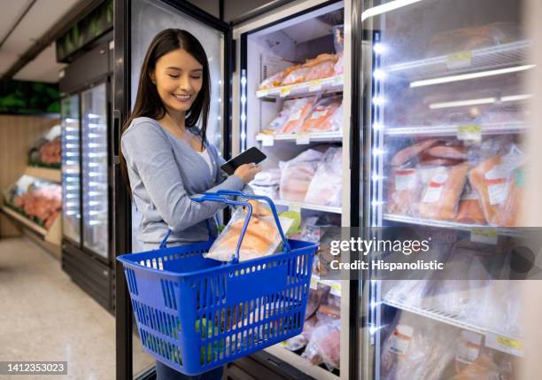frau kauft meeresfrüchte im supermarkt - gefrierschrank stock-fotos und bilder