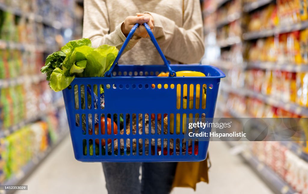 Frau im Supermarkt trägt einen Einkaufskorb