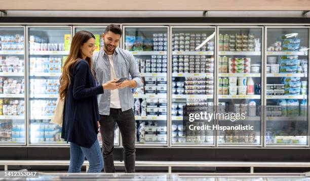 paar, das lebensmittel im supermarkt kauft, folgt einer einkaufsliste - supermarket refrigeration stock-fotos und bilder