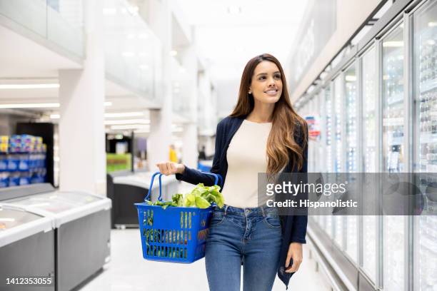 mulher fazendo compras no supermercado na seção refrigerada - cesta de compras - fotografias e filmes do acervo