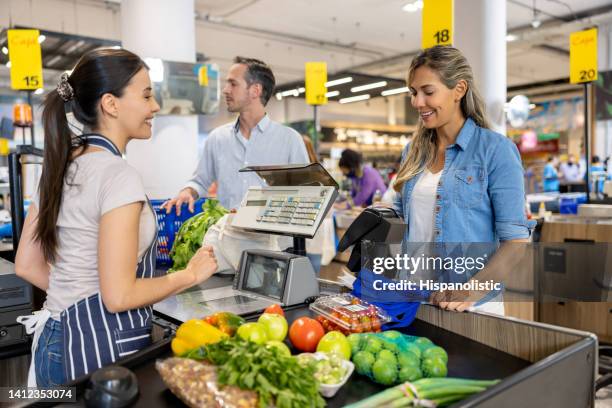 frau, die im supermarkt einkauft und mit karte an der kassiererin bezahlt - ladenkasse stock-fotos und bilder