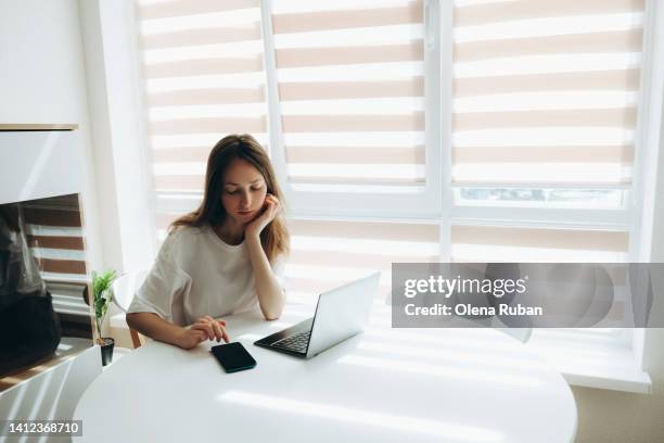 young woman working on laptop at the table indoors. - wait photos et images de collection