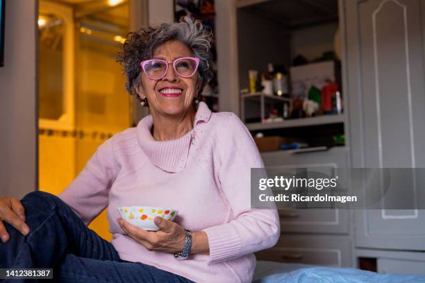 elderly woman is enjoying her lunch while watching tv - ethnicity stock pictures, royalty-free photos & images