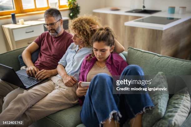 maried caucasian couple watching movie on laptop, while their daughter using digital tablet - lazy husband stock pictures, royalty-free photos & images
