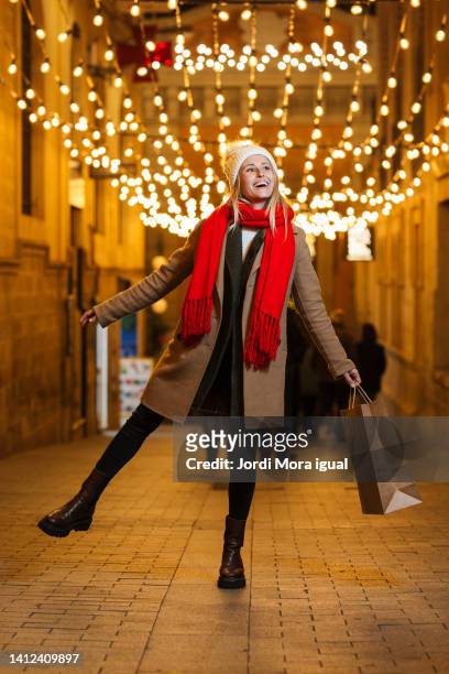 cute woman walking in street market with shopping bags, looking into the windows of stores and warehouses.. - winter barcelona stock pictures, royalty-free photos & images
