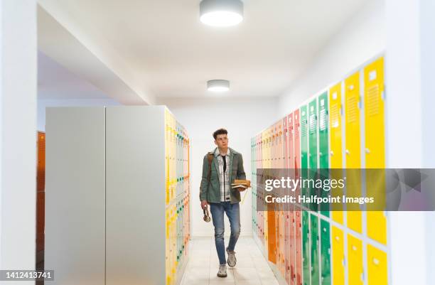 front view of teenage boy in locker room, full length. - school locker room stock pictures, royalty-free photos & images