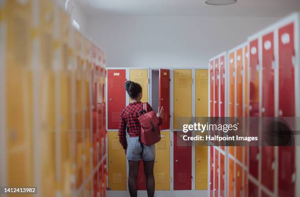rear view of teenage girl in locker room. - red lockers stock pictures, royalty-free photos & images